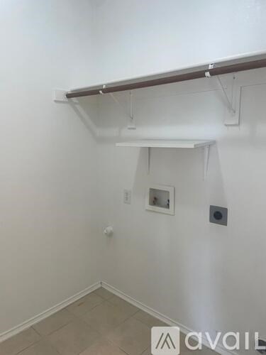 A room with a white wall and a brown shelf.