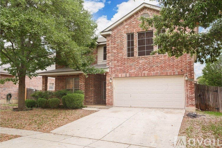 A house with a garage and a tree in front.