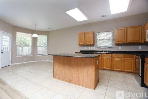 A kitchen with wooden cabinets and black countertops.