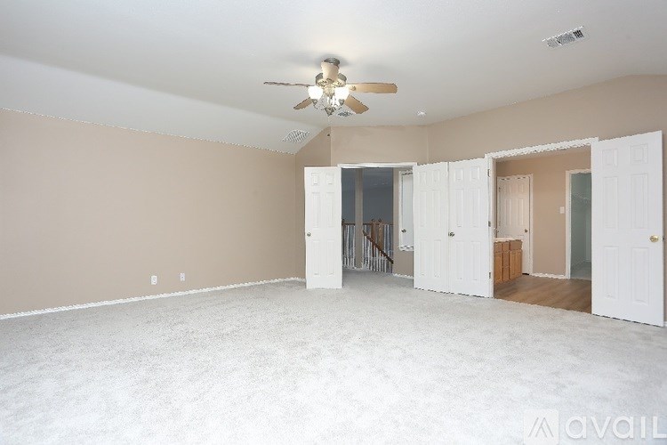 A spacious room with a ceiling fan and a doorway leading to another room.
