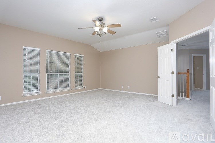 A spacious room with a ceiling fan and carpeted floor.