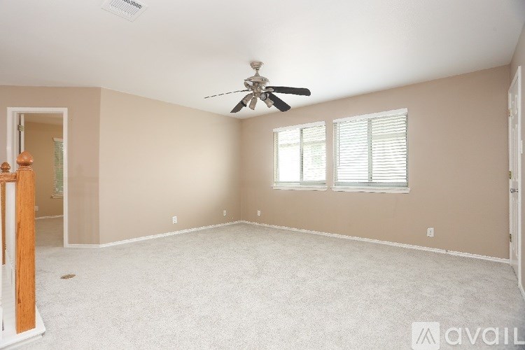 A spacious room with a ceiling fan and carpeted floor.