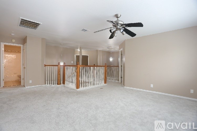 A spacious room with a ceiling fan and a railing in the middle.