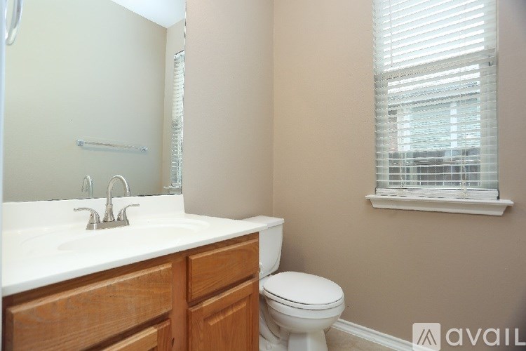 A bathroom with a toilet, sink, and mirror.