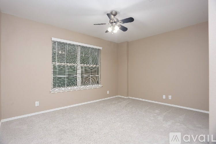 A room with a ceiling fan and a window with blinds.