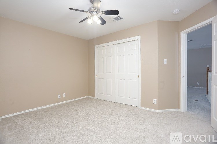 A room with a ceiling fan and a white door.