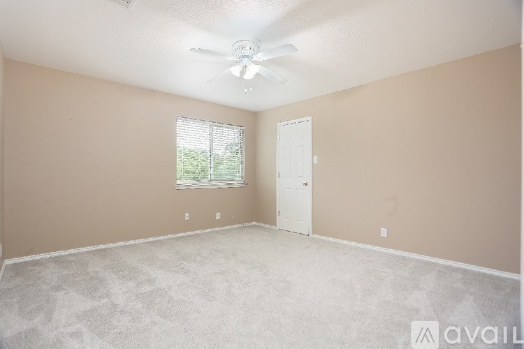 A room with a ceiling fan and a window with blinds.