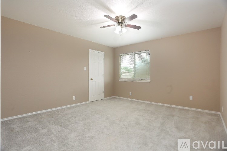 A room with a ceiling fan and a window with blinds.