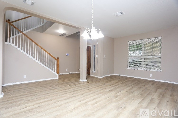 A spacious room with wooden flooring and a staircase.