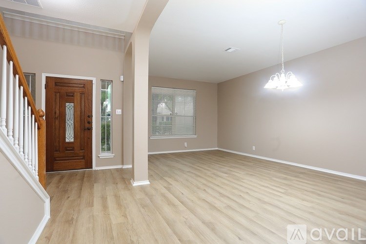 A spacious room with wooden flooring and a chandelier hanging from the ceiling.