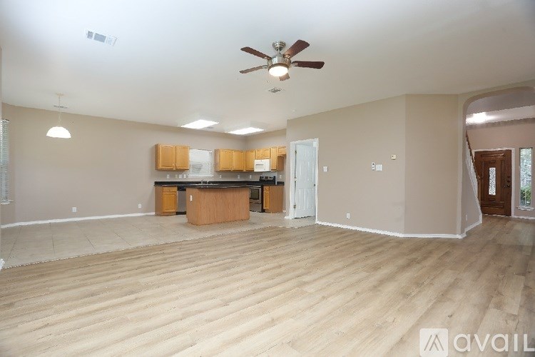 A spacious room with wooden flooring and a ceiling fan.
