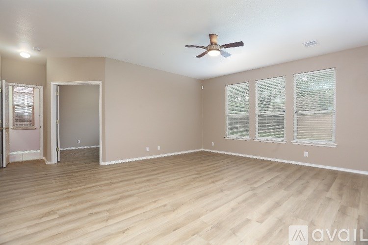 A spacious room with a ceiling fan and wooden flooring.