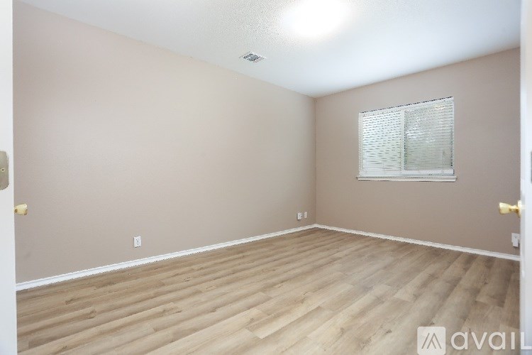 A room with wooden flooring and a window with blinds.