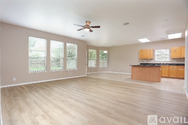 A spacious room with wooden flooring and a ceiling fan.