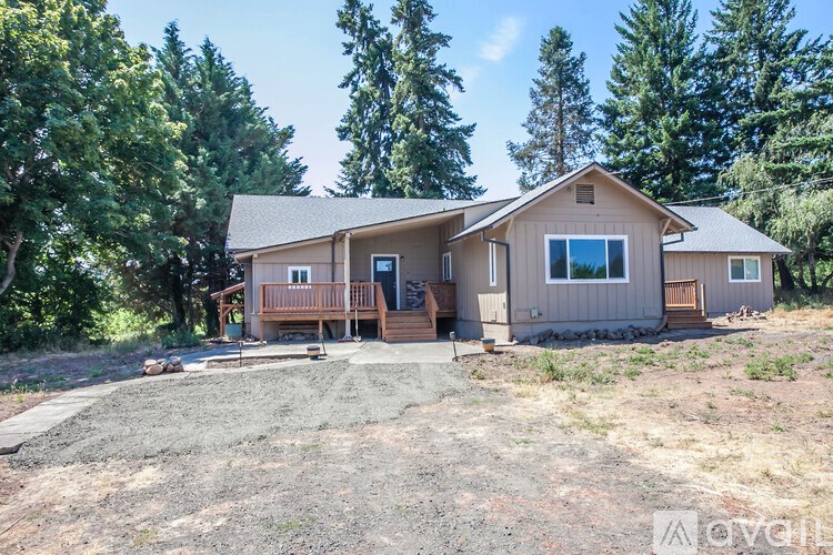 A house with a brown roof and a porch is surrounded by trees.