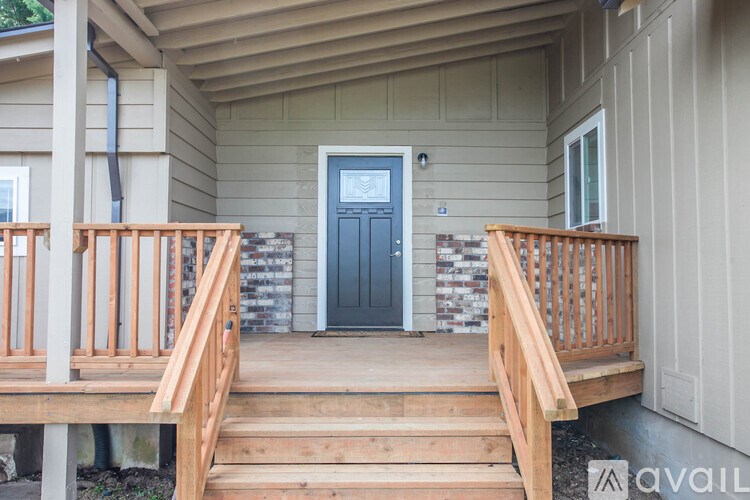 A wooden deck leads to a blue door on a house.