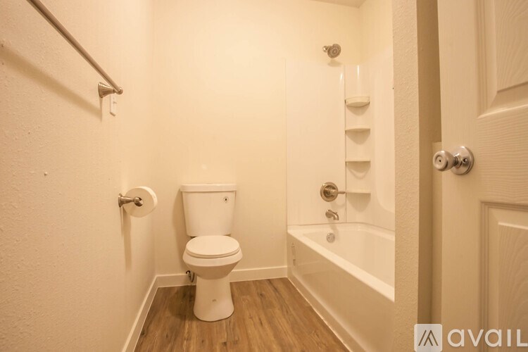 A white toilet in a small bathroom with a wooden floor.