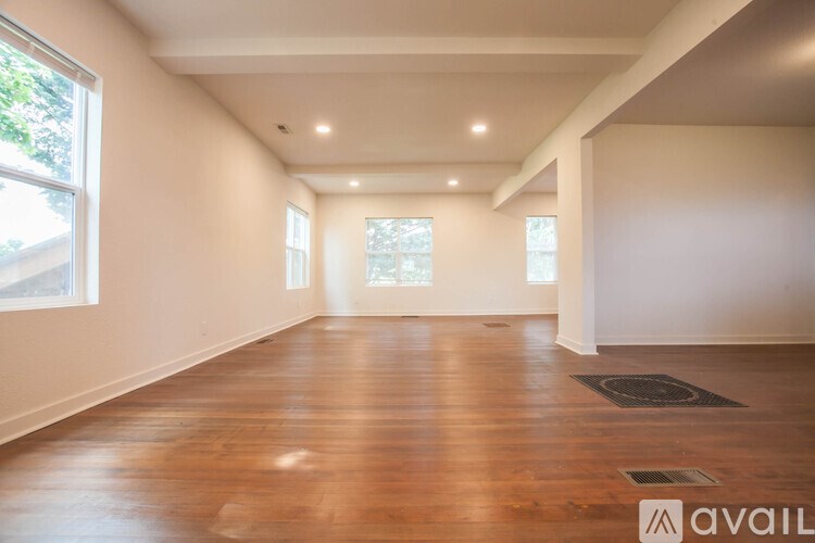 A spacious room with wooden floors and white walls.
