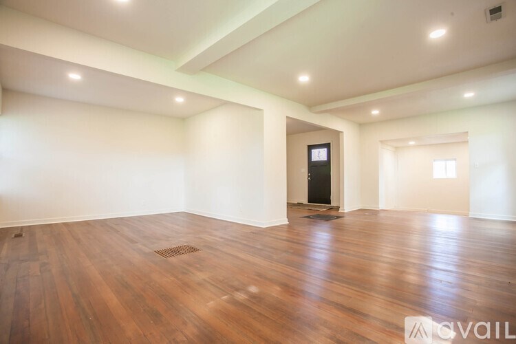 A spacious room with wooden floors and a central heating unit.