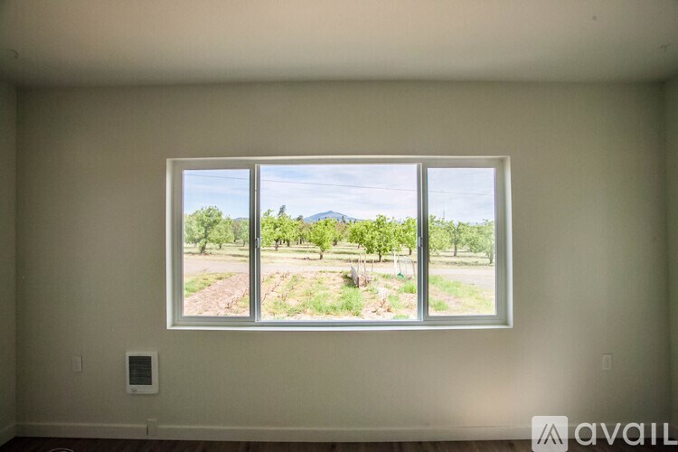 A room with a large window overlooking a field.