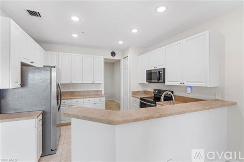 A kitchen with white cabinets and a refrigerator.