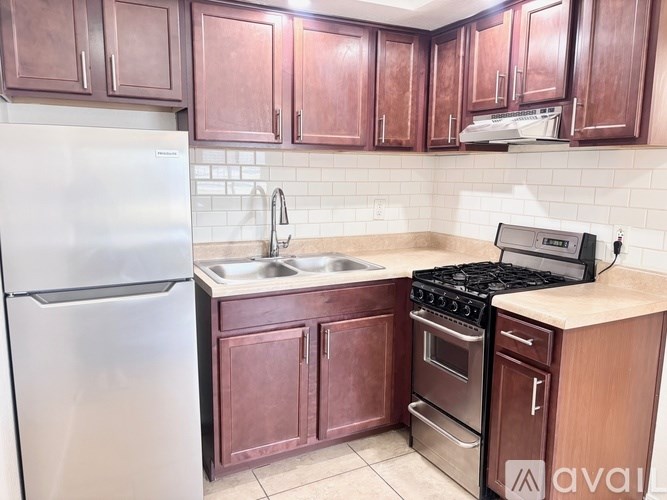 A kitchen with wooden cabinets and a stainless steel refrigerator.
