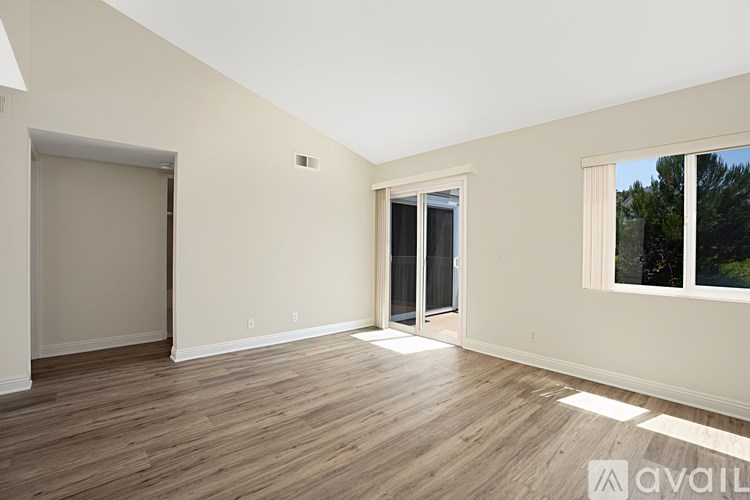 A room with wooden flooring and a window showing trees outside.