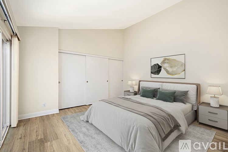 A bedroom with a large bed, a nightstand, and a painting on the wall.