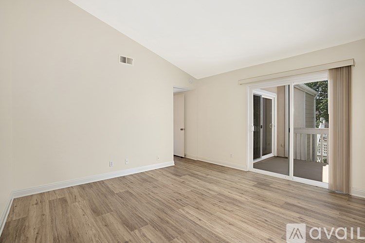 A room with wooden flooring and a sliding glass door.