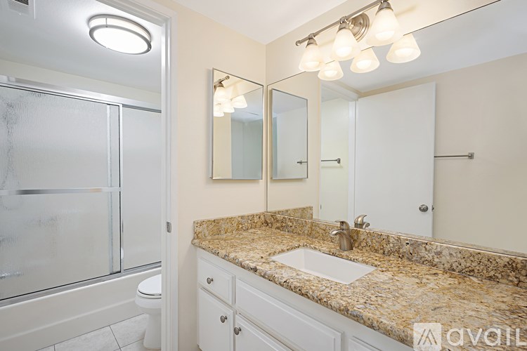 A bathroom with a granite countertop and a walk-in shower.