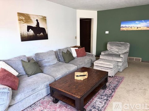 A living room with a grey couch, a coffee table, and a painting of a cowboy on the wall.