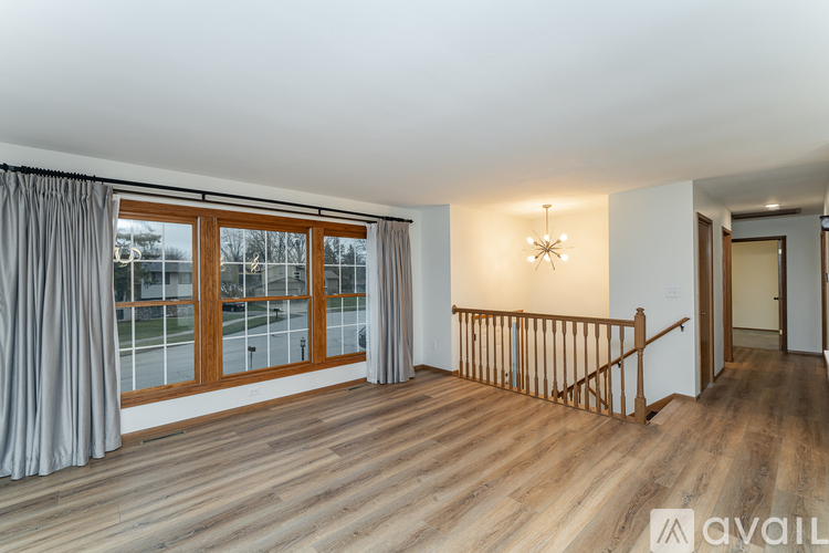 A room with wooden floors and a large window with curtains.