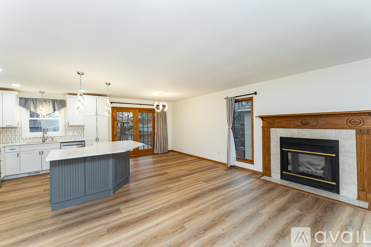 A spacious living room with a fireplace and a kitchen area.