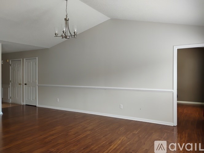 A room with a chandelier and wood flooring.