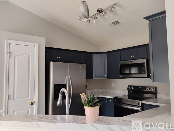 A kitchen with a white door, black cabinets, and a marble countertop.