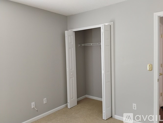 A room with a white door and a carpeted floor.