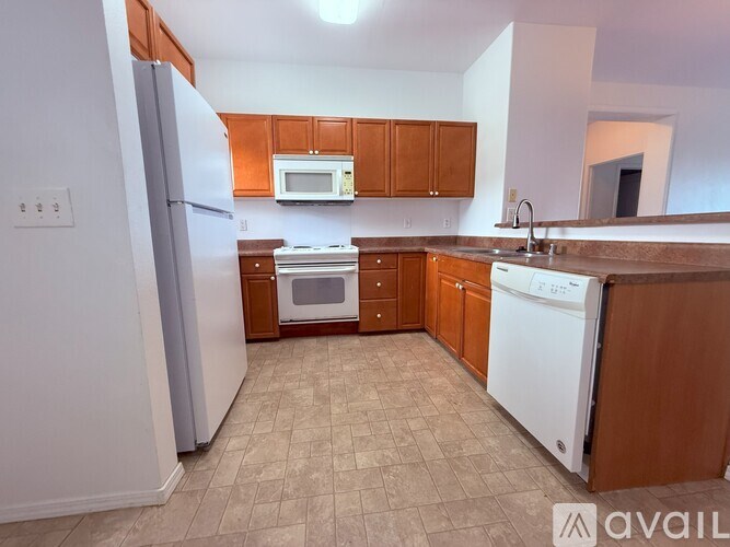 A kitchen with brown cabinets and a white dishwasher.