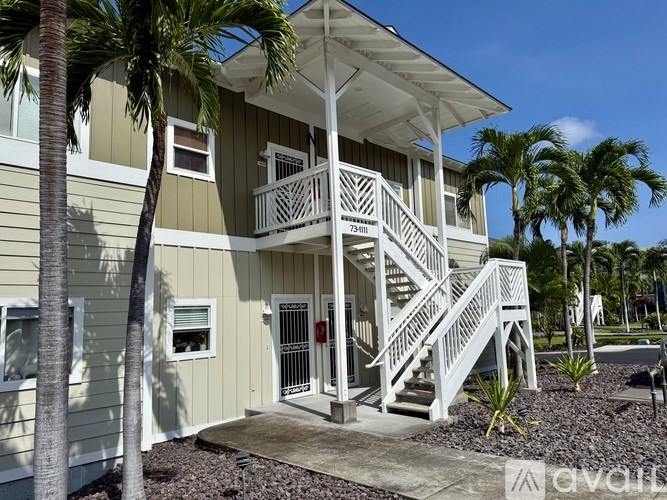 A two-story house with a balcony and stairs leading to the front door.