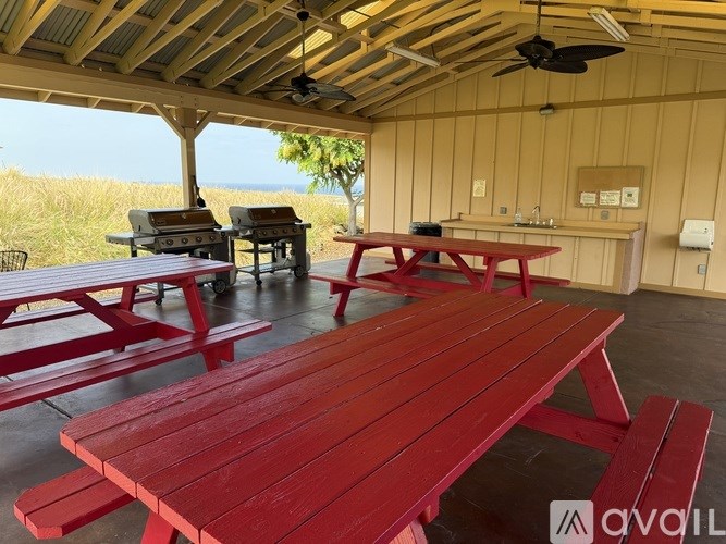 A covered picnic area with red benches and tables.