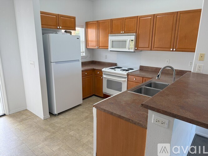 A kitchen with brown cabinets and a white refrigerator.