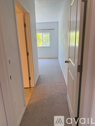 A hallway with a carpeted floor and white walls.