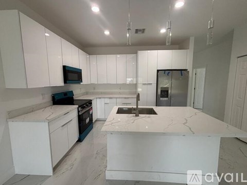 A kitchen with white cabinets and a marble island.
