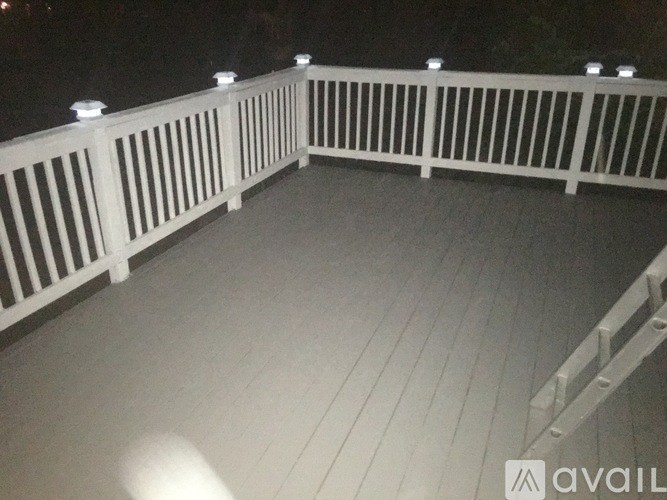 A deck with white railings and lights on top.