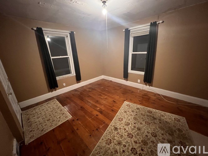 A room with two windows and wooden flooring.