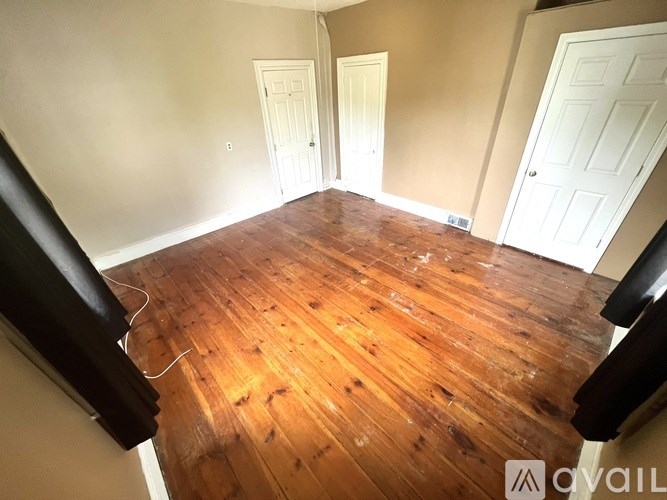 A room with wooden flooring and two white doors.