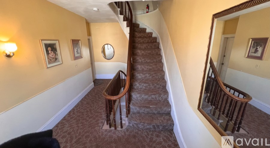 A staircase with a wooden banister and a round mirror on the wall.