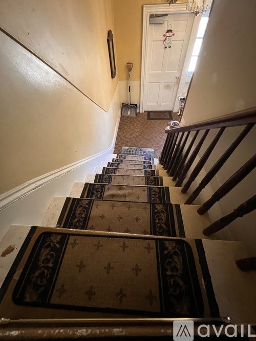 A staircase with a black and gold runner.