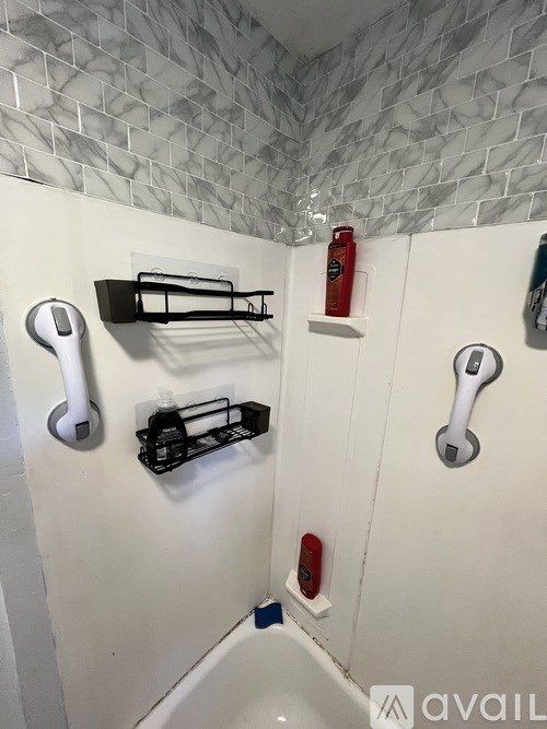 A bathroom with a white tub and a white shower with a black soap dish.