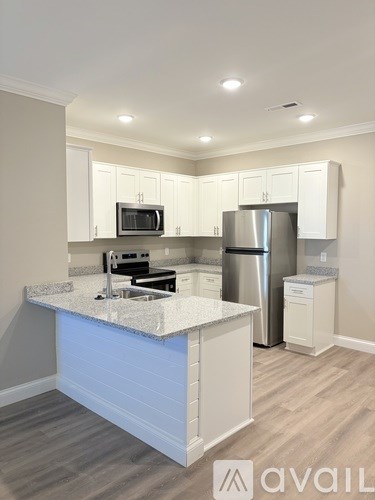 A kitchen with white cabinets and a marble countertop.