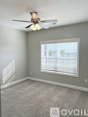 A room with a ceiling fan and a window with blinds.